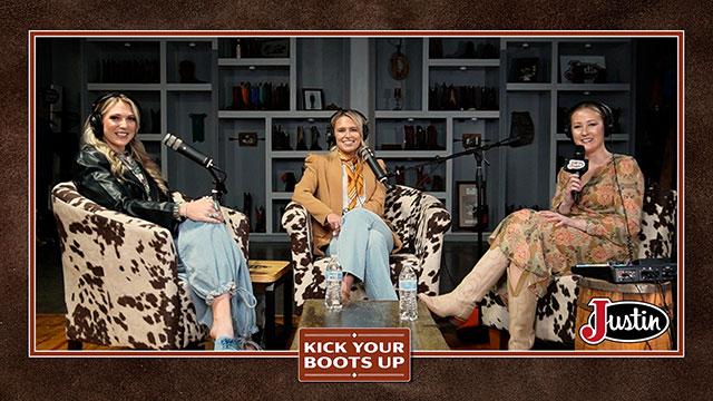 Three women with blonde hair looking at the camera, smiling, and sitting in chairs having a conversation.